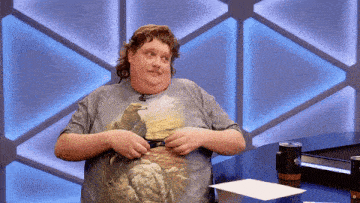 a man wearing a shirt with an eagle on it is standing in front of a table