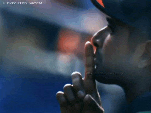 a man wearing a baseball cap holds his finger to his mouth