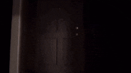 a man is standing in a dark room holding a gun in his hand .