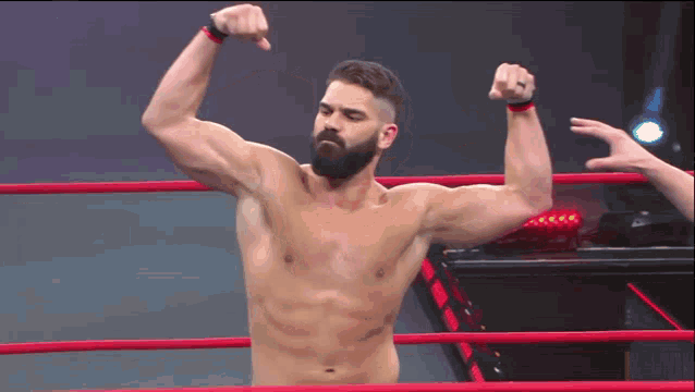 a shirtless wrestler flexes his muscles in the ring
