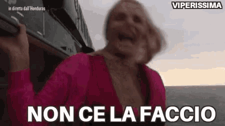 a woman in a pink shirt is standing next to a train and says `` non ce la faccio '' .