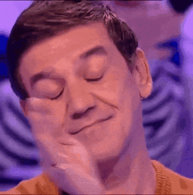 a man with his eyes closed is making a funny face .