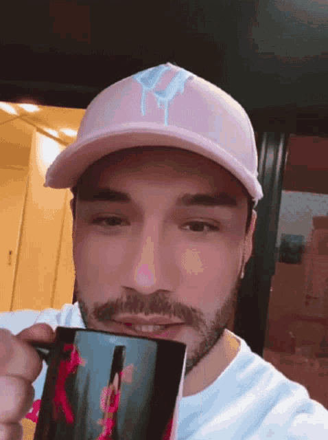 a man wearing a pink hat is holding a mug