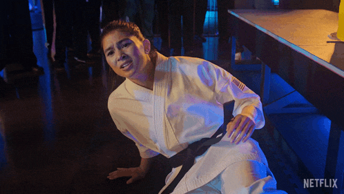 a woman in a karate uniform is laying on the floor with a netflix logo visible