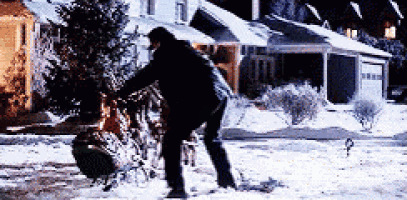 a man is pushing a sleigh through the snow in front of a house