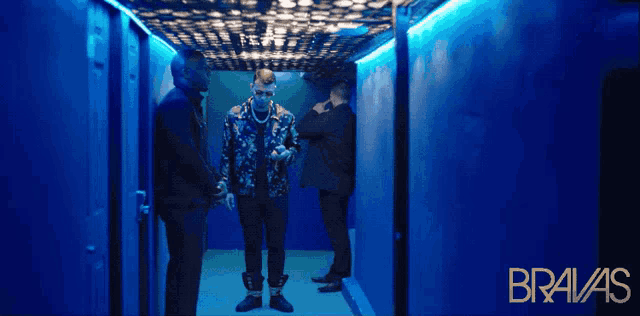 three men standing in a hallway with bravas written on the bottom right