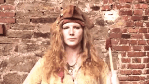 a woman with long red hair wearing a pirate hat