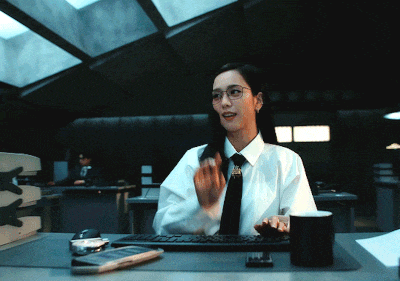 a woman in a white shirt and tie is sitting at a desk