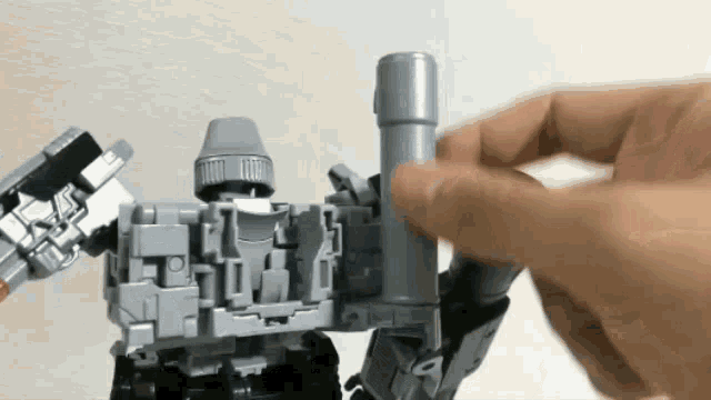 a person is holding a toy robot in their hand and playing with it .