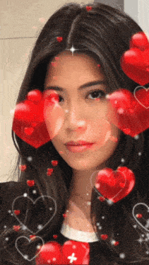 a woman is surrounded by red hearts and has a cross on her face