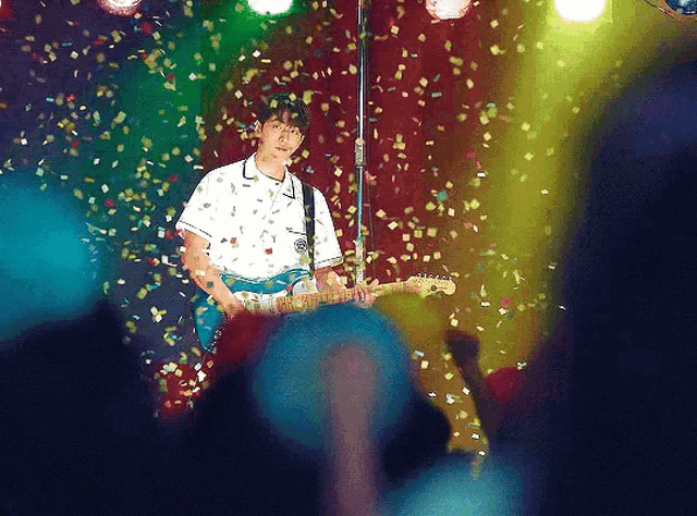 a man playing a guitar on a stage with confetti falling