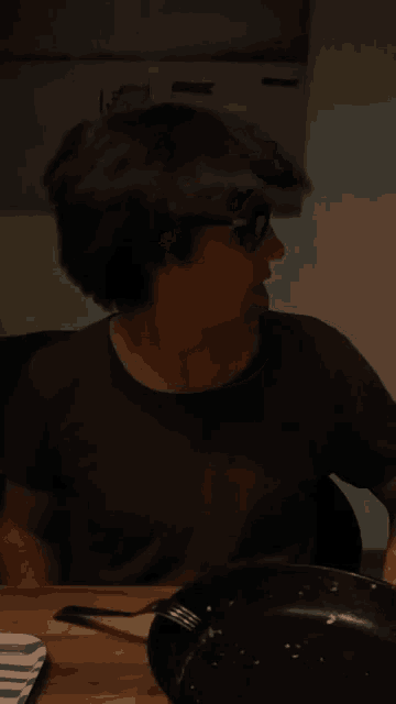 a man wearing glasses is sticking his tongue out while sitting at a table