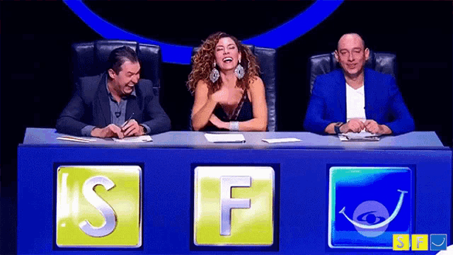 three people are sitting at a table with the letters s and f on them