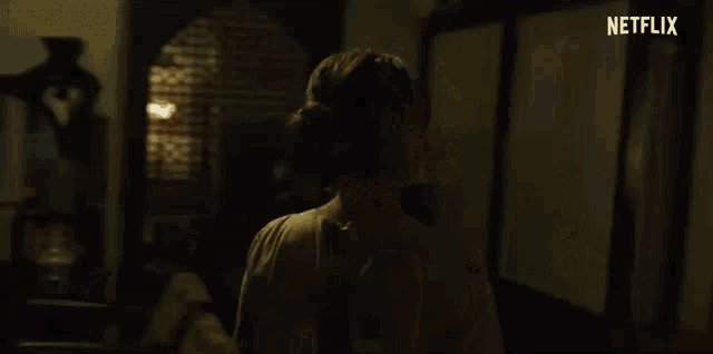 a man is holding a woman 's neck in a dark room in a netflix movie .
