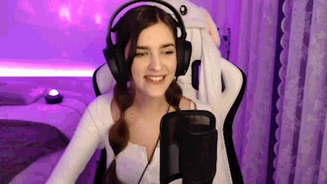 a woman wearing headphones and a bunny hat is sitting in a gaming chair .