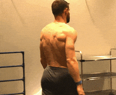 a man without a shirt is standing in front of a shelf