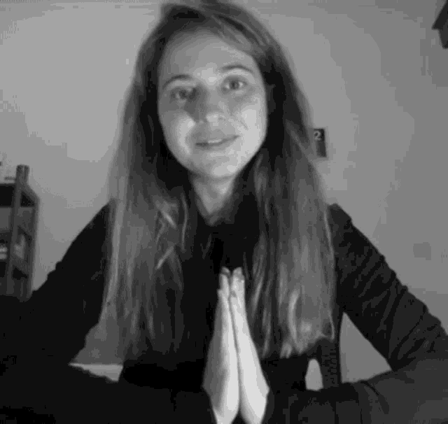 a woman with her hands folded in front of her face