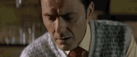a man in a suit and tie is sitting down with his eyes closed and a bloody forehead .