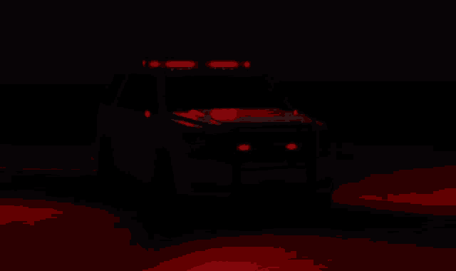 a white suv with red lights on the hood is parked in the dark