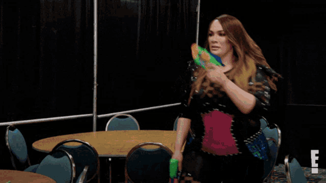 a woman holding a water gun in front of a table and chairs