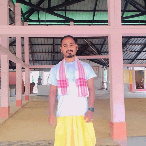 a man wearing a white shirt and a pink towel around his neck poses for a picture