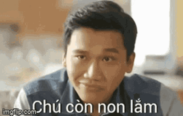 a man is making a funny face with the words `` chu con non lam '' written below him .