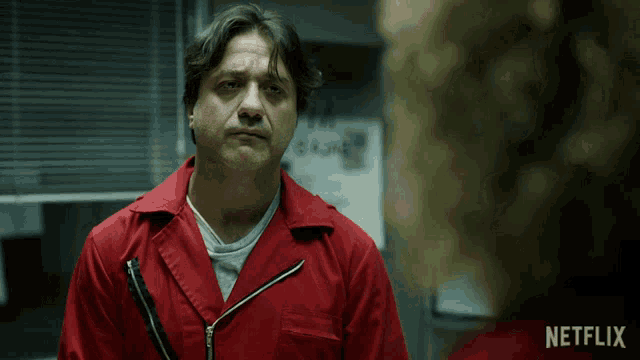 a man in a red jumpsuit is standing in front of a netflix logo