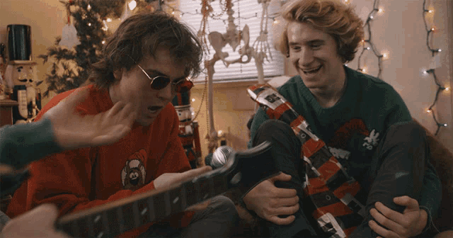 a man playing a guitar with a sweater that says ' christmas ' on it