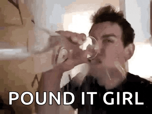 a man is drinking from a glass with the words `` pound it girl '' written on the bottom .