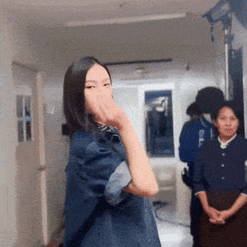 a woman in a denim jacket covering her mouth with her hand