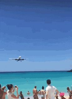 a plane is flying over a beach and people are watching