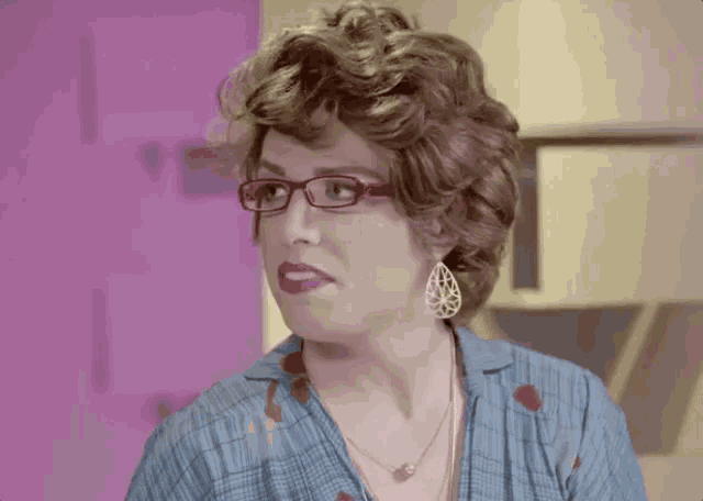 a woman wearing glasses and a pearl necklace looks at the camera