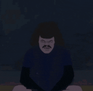 a man with a mustache is standing in the dark looking at the camera .