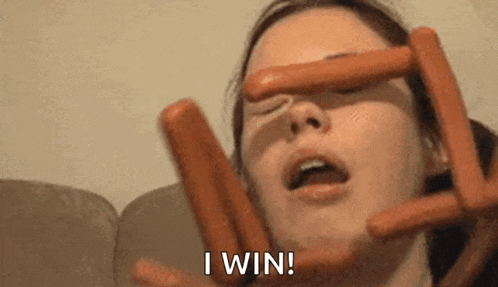 a woman is holding hot dogs in front of her face .