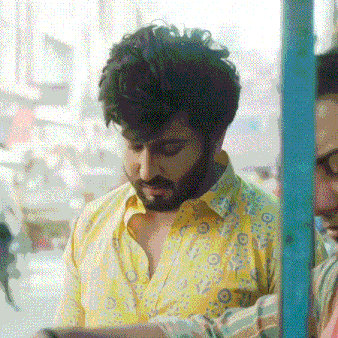 a man with a beard is wearing a yellow shirt and looking down .