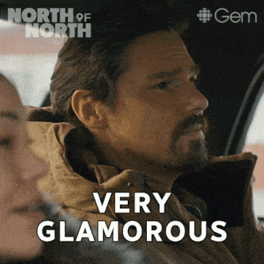 a man in a car says very glamorous in front of a north of north poster