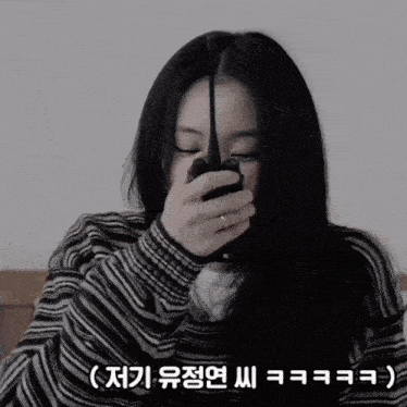 a woman in a striped sweater holds a walkie talkie to her face