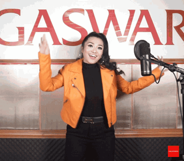a woman is singing into a microphone in front of a gaswar sign