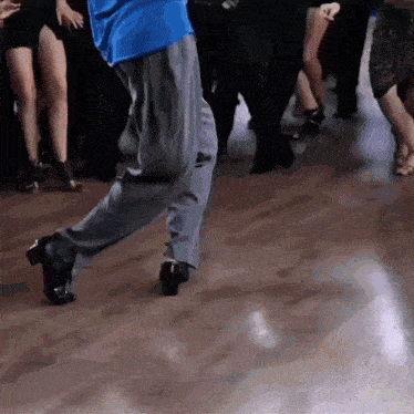 a man in a blue shirt is dancing with a group of people