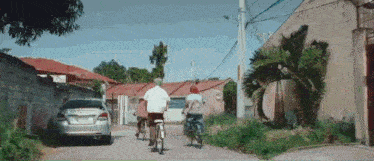 a group of people are riding bicycles down a street in a residential area .