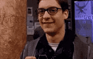 a man wearing glasses is smiling while holding a cell phone in his hand .