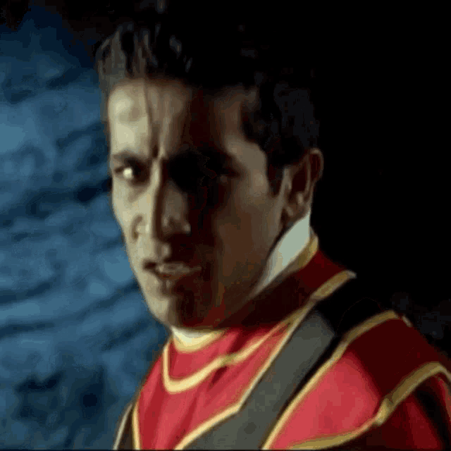 a man in a red and gold costume looks at the camera