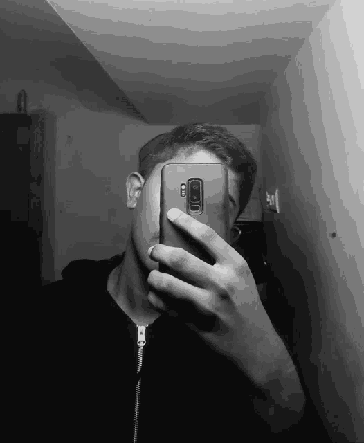 a man taking a picture of himself with a samsung cell phone