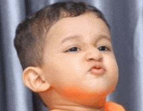a baby is making a funny face and blowing a kiss at the camera .