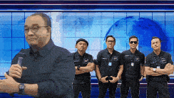 a group of men are standing in front of a blue wall