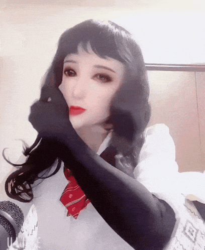 a woman wearing black gloves and a red tie is covering her face