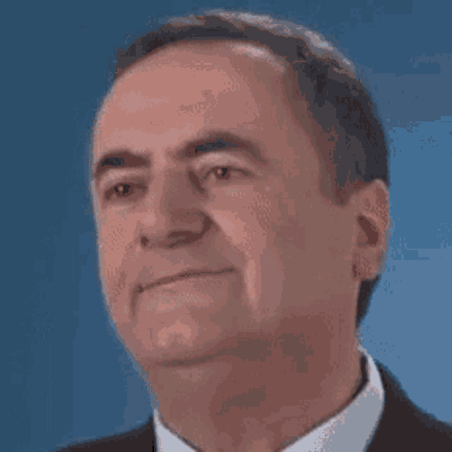 a man in a suit and tie is smiling for the camera against a blue background .