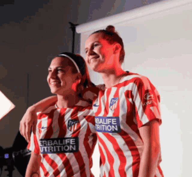 two women wearing red and white striped shirts with herbalife trition written on them
