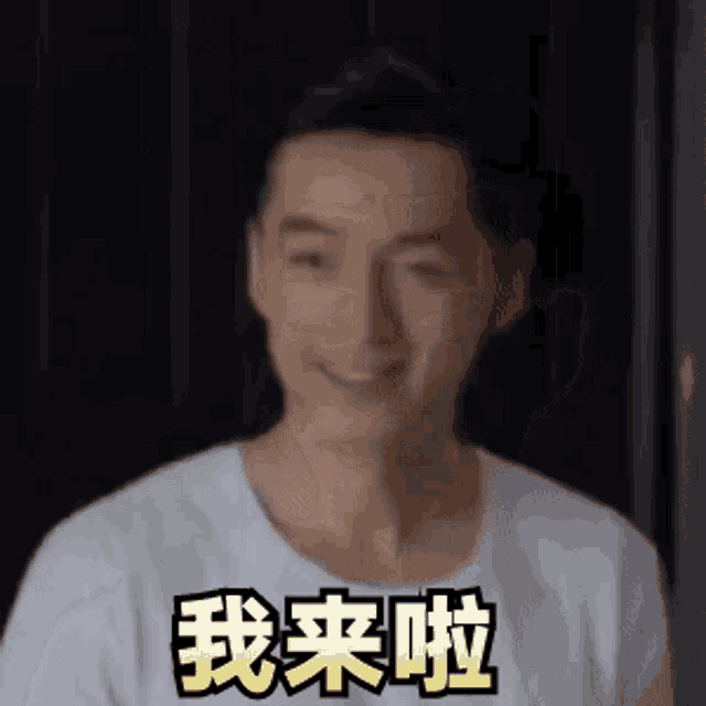 a man in a white shirt is smiling and making a funny face with chinese writing on it .