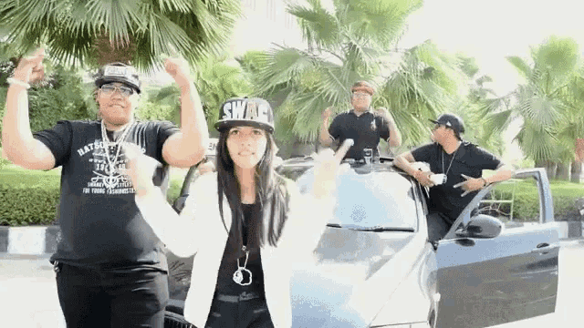 a woman wearing a swag hat stands in front of a group of men